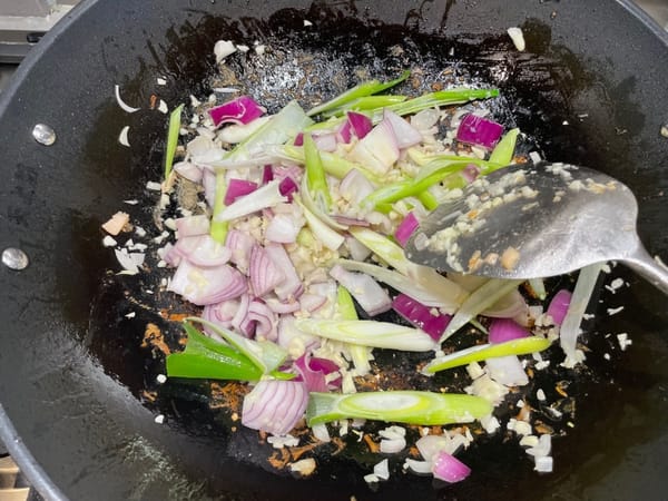 Faites ensuite revenir la pâte de curry. Ajoutez un peu d’huile dans le wok d’origine et faites revenir les oignons, l’ail, les oignons verts, les échalotes et les autres ingrédients.