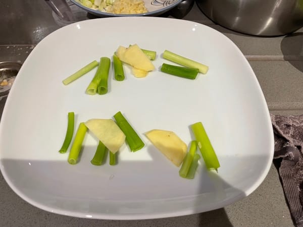 Coloque rodajas de jengibre y segmentos de cebolleta en un plato.