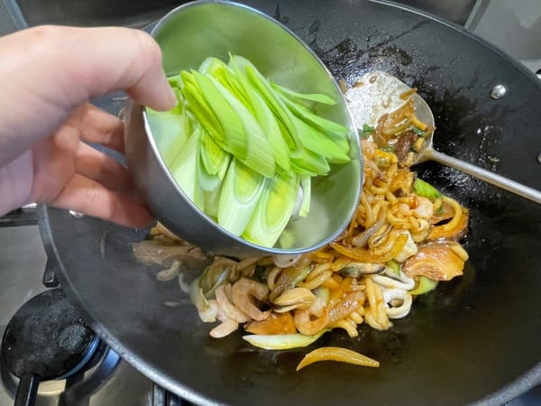 Después de abrir la tapa, agregue nuevamente los mariscos y saltee, luego agregue las cebolletas y saltee por último.