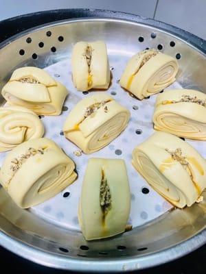 Unte con aceite la rejilla de la vaporera o cúbrala con papel antiadherente, coloque las piezas de masa cortadas sobre ella, vierta agua caliente a unos 60 °C en la olla y deje reposar la masa durante 20 minutos. Antes de que suba, haga un corte en el centro de la masa, exprima un poco de jarabe de azúcar moreno líquido, espolvoree con nueces tostadas picadas y espere a que la masa haya subido 1,5 veces su volumen original antes de cocinarla al vapor durante 13 minutos. Después de apagar el fuego, deje reposar 5 minutos.