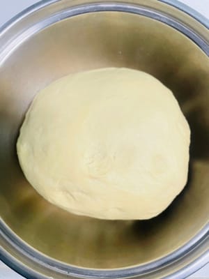 Agregue 5 g de manteca de cerdo, 250 g de harina, 3 g de levadura y 2 g de sal al agua con azúcar morena enfriada, vierta todo en el tazón y amáselo hasta obtener una masa suave.