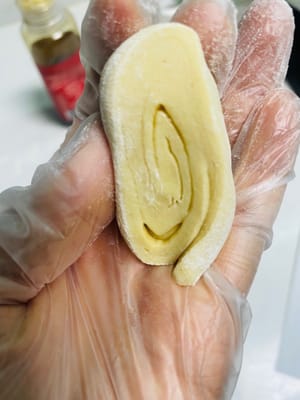 Espolvorea harina seca sobre la superficie de trabajo, retira la masa levada, añade un poco más de harina y amásala hasta que puedas abrirla con un cuchillo y no veas ningún agujero de aire visible en los lados. ¡Este paso es clave para una superficie lisa para los bollos al vapor!