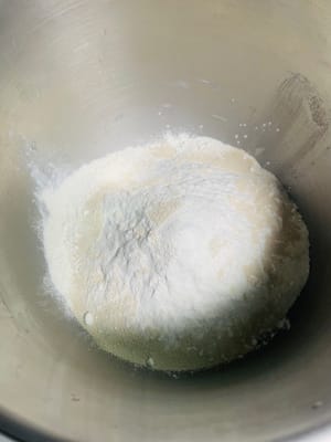 Agregue 5 g de manteca de cerdo, 250 g de harina, 3 g de levadura y 2 g de sal al agua con azúcar morena enfriada, vierta todo en el tazón y amáselo hasta obtener una masa suave.