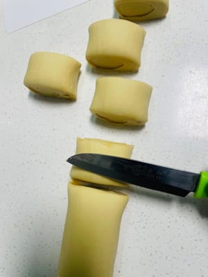 Extender la masa amasada en una lámina fina, pincelarla con una capa de jarabe de azúcar moreno líquido, luego enrollarla firmemente, asegurándose de que no queden huecos, y luego cortarla en trozos pequeños de unos 3 cm de largo.