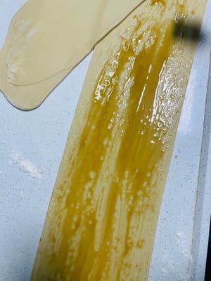 Extender la masa amasada en una lámina fina, pincelarla con una capa de jarabe de azúcar moreno líquido, luego enrollarla firmemente, asegurándose de que no queden huecos, y luego cortarla en trozos pequeños de unos 3 cm de largo.