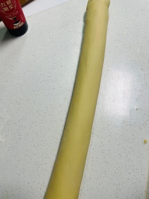 Extender la masa amasada en una lámina fina, pincelarla con una capa de jarabe de azúcar moreno líquido, luego enrollarla firmemente, asegurándose de que no queden huecos, y luego cortarla en trozos pequeños de unos 3 cm de largo.