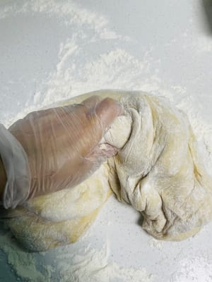 Espolvorea harina seca sobre la superficie de trabajo, retira la masa levada, añade un poco más de harina y amásala hasta que puedas abrirla con un cuchillo y no veas ningún agujero de aire visible en los lados. ¡Este paso es clave para una superficie lisa para los bollos al vapor!