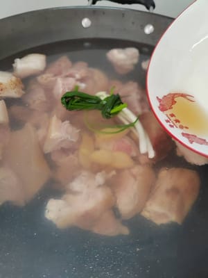 Mettetelo nella pentola a sbollentare, aggiungete tre fette di zenzero, uno spicchio di cipollotto e un cucchiaio di vino da cucina per togliere l'odore di pesce e fate bollire a fuoco alto.