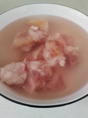 Per prima cosa preparate una bacinella d'acqua e aggiungete un cucchiaino di sale, poi versate gli zampetti di maiale e lasciateli in ammollo per 15 minuti, il che aiuterà ad eliminare efficacemente il sangue e l'odore di pesce.