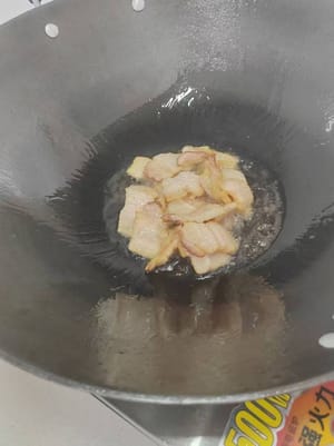 Vierta aceite en la sartén. Cuando esté caliente, añada la panceta cortada en rodajas y saltee un rato hasta que se elimine el exceso de grasa.