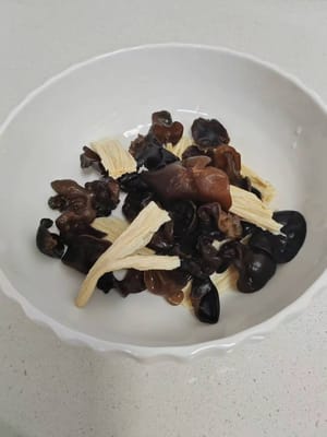 Vierta agua en una olla y llévela a ebullición. Añada los palitos de tofu y el hongo negro, y blanquéelos durante aproximadamente 1 minuto. Retire y reserve.