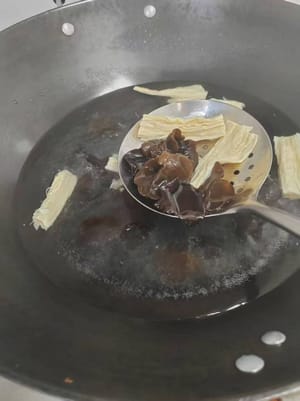 Versez de l'eau dans une casserole et portez à ébullition. Ajoutez les bâtonnets de tofu et les champignons noirs, et blanchissez pendant environ 1 minute. Retirez et réservez.