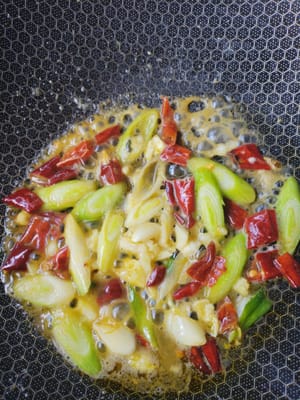 Calentar el aceite en una sartén y saltear el ajo, los brotes de ajo y los chiles hasta que estén fragantes.