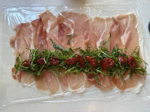 Usap minyak berlebih pada tomat dan letakkan di atas daun arugula