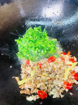 다음으로, 다진 고기를 냄비 한쪽으로 밀어두고, 다진 겨자잎 피클을 붓고 몇 초간 빠르게 볶습니다. 그런 다음 다진 고기와 다른 반찬들과 함께 골고루 볶습니다.