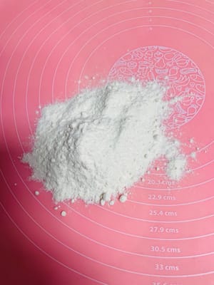 操作台上撤上干面粉防沾，将发酵好的面团拿出来，继续揉，排气。