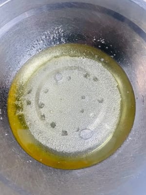 Tuang minyak jagung, gula, dan air ke dalam mangkuk dan aduk hingga gula larut.