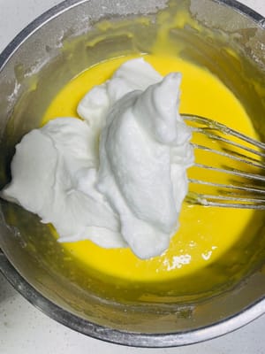 Tomar un tercio del merengue y añadirlo a la masa de yemas. Mezclar cortando y mezclando. No remover con demasiada fuerza, ya que las claras se desinflarán y el pastel no subirá.