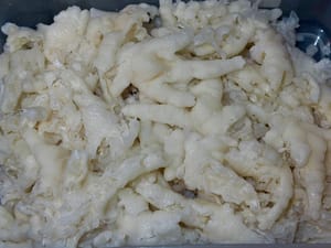 Pertama, masukkan ceker ayam tanpa tulang yang sudah dicairkan, serai, irisan jahe, garam, dan anggur masak ke dalam panci besar berisi air dingin dan didihkan. Rebus sebentar selama 3 hingga 4 menit.