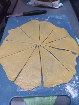 Après 15 minutes, saupoudrez la planche de cuisine de farine et prenez un peu de pâte, étalez-la finement et coupez-la en plusieurs morceaux.