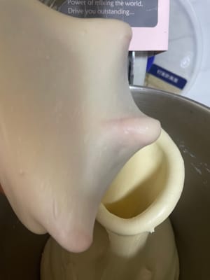 加入软化好的黄油,先低速揉2分钟让黄油完全吃进去,再转高速8分钟左右揉到能拉出薄薄的手套膜,边缘光滑无锯齿就行。