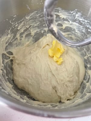 加入软化好的黄油,先低速揉2分钟让黄油完全吃进去,再转高速8分钟左右揉到能拉出薄薄的手套膜,边缘光滑无锯齿就行。
