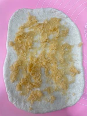 240g椰蓉辫子包:
把面团擀平,铺上椰蓉酱,折好再轻轻压扁。
用刀切成三条(顶端别切断),有椰蓉的一面朝上,像编辫子一样编起来,收口捏紧。
把两端向里卷成一个圆,放进240g的一次性面包盒里发酵。