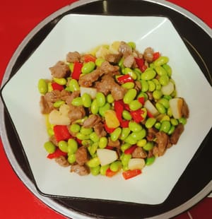 Un plato de edamame salteado y carne cortada en cubitos está listo, fresco, fragante y delicioso.