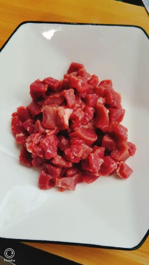 potong dadu daging sapi yang sudah dibersihkan, tambahkan minyak goreng supaya empuk, garam, kecap asin, saus tiram, tepung maizena, minyak merica, dan bubuk merica, aduk rata, sisihkan.