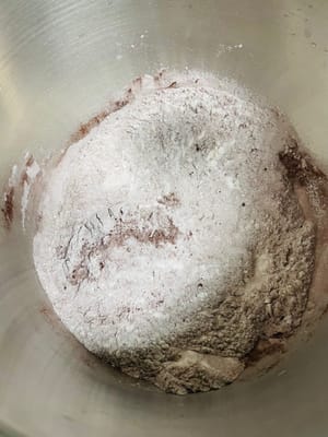 Versare la farina ad alto contenuto di glutine, il cacao in polvere, il latte in polvere, il lievito secco e il sale nella ciotola e mescolare bene.