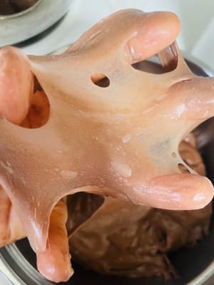 Aggiungere il burro ammorbidito e impastare a bassa velocità per 3 minuti per incorporarlo completamente all'impasto. Quindi impastare ad alta velocità per 8 minuti fino a formare una membrana sottile e liscia (la chiave per un pane morbido).