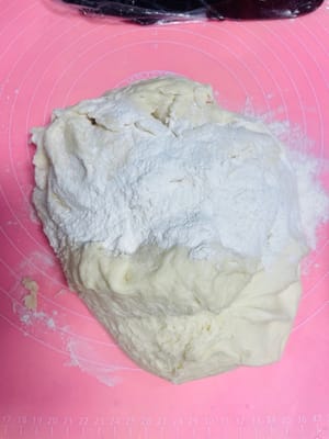 作業台に薄力粉を振り、膨らんだ生地をその上に乗せます。

さらに薄力粉を少し加え、生地を切ったときに大きな空気穴が見えなくなるまでしばらくこねます。

この工程は、なめらかでツヤのある蒸しパンや美しい花巻きを作るための鍵です。見た目を気にするなら、この工程を省略しないでください！
