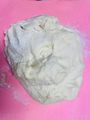 作業台に薄力粉を振り、膨らんだ生地をその上に乗せます。

さらに薄力粉を少し加え、生地を切ったときに大きな空気穴が見えなくなるまでしばらくこねます。

この工程は、なめらかでツヤのある蒸しパンや美しい花巻きを作るための鍵です。見た目を気にするなら、この工程を省略しないでください！