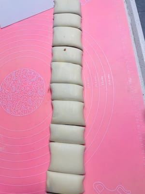 生地を幅の異なる2種類の細長い帯状に切ります。大きい方の帯は約3.5cm幅、小さい方の帯は約2cm幅です。小さい方の帯を大きい方の帯の上に重ねます。