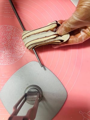 麺を15cmくらいの長さに伸ばし、箸で真ん中をねじり、両端をしっかりとつまんでから、箸で軽く押さえます。

（この手順は動画でより分かりやすく説明しています。箸は下から抜くことを忘れないでください。）