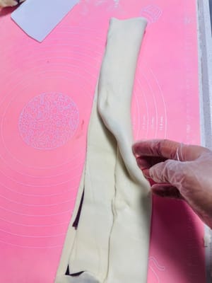 私はパスタマシンを使って生地を薄く伸ばしました。手で伸ばす場合は、厚さ2mm以下、幅25cm、長さ30cm以上に伸ばしてください。

写真参照：伸ばしたあんこシートを生地シートの半分に置き、もう半分で覆います。

手で軽く伸ばし、3分の1のところからさらに半分に折ります。

麺棒を使って軽く平らに伸ばすと、あんこが生地にしっかりと密着します。