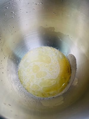 ボウルにイースト、食用油、塩、温水を入れて混ぜ、溶けたら小麦粉と砂糖を加えます。

生地が滑らかになり、べたつかなくなるまで、ドウミキサーを使うか手でこねます。