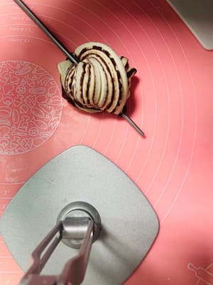 麺を15cmくらいの長さに伸ばし、箸で真ん中をねじり、両端をしっかりとつまんでから、箸で軽く押さえます。

（この手順は動画でより分かりやすく説明しています。箸は下から抜くことを忘れないでください。）