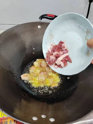 放5片蒜倒入腌制好的瘦肉翻炒均匀，倒入青椒火腿肠，继续翻炒。