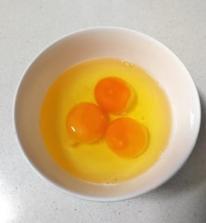 Rompa tres huevos de gallinas camperas en un bol y resérvelos.