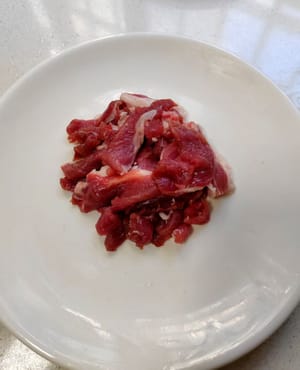 Cortar la carne magra en trozos pequeños, espolvorear 2 gramos de sal, 1 cucharadita de salsa de soja y un poco de fécula de maíz y marinar durante 2-3 minutos.
