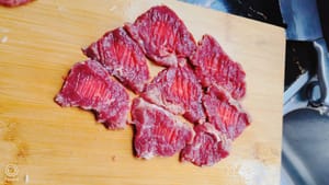 包丁の背で牛肉を軽く叩き、味を染み込ませます。ステーキを柔らかくするコツは、適量の塩と白ワイン8～10mlを入れたきれいな水に10分間浸し、その後、きれいな水で数回すすいでから取り出すことです。
