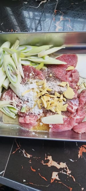 キッチンペーパーで洗った肉を拭き、みじん切りにしたネギ、千切りにした生姜、適量のコーンスターチ、醤油15ml、料理酒10ml、塩2グラム、黒コショウ20グラム、食用油15mlを加えてよく混ぜ、10分間マリネします。
