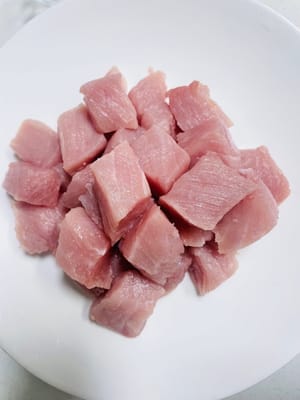 Das Schweinefilet längs der Faser in 3 cm große Würfel schneiden (das Schneiden längs der Faser erleichtert das Anbraten, siehe Bild).