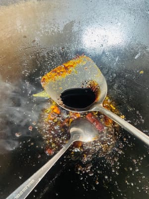 Zutaten anbraten und Brühe zubereiten. Einen Wok mit kaltem Öl bei niedriger Hitze erhitzen. Zuerst Ingwerscheiben anbraten, bis sie duften, dann Kandiszucker hinzufügen und unter Rühren karamellisieren lassen. Pixian-Chilibohnenpaste hinzufügen und unter Rühren anbraten, bis das Öl rot wird. Anschließend die restlichen Gewürze hinzufügen und unter Rühren anbraten. So viel heißes Wasser angießen, dass die Schweinshaxe bedeckt ist, und etwa 1 Esslöffel Salz hinzufügen (abschmecken; die Brühe sollte leicht salzig sein). Zum Kochen bringen und dann vom Herd nehmen. Durch das Anbraten von Zucker und Chilibohnenpaste erhält die Brühe ihre rote, glänzende Farbe, die Gewürze sorgen für einen reichhaltigeren Geschmack.