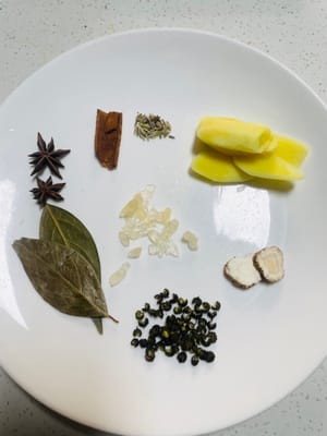 Siapkan bumbu. Iris jahe, lalu siapkan adas bintang, daun salam, merica Sichuan, biji adas, kayu manis, dan gula batu. Jika Anda tahan pedas, tambahkan cabai kering—bumbu-bumbu ini penting untuk meningkatkan cita rasa daging babi.