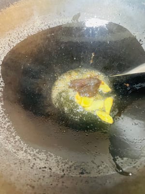 Zutaten anbraten und Brühe zubereiten. Einen Wok mit kaltem Öl bei niedriger Hitze erhitzen. Zuerst Ingwerscheiben anbraten, bis sie duften, dann Kandiszucker hinzufügen und unter Rühren karamellisieren lassen. Pixian-Chilibohnenpaste hinzufügen und unter Rühren anbraten, bis das Öl rot wird. Anschließend die restlichen Gewürze hinzufügen und unter Rühren anbraten. So viel heißes Wasser angießen, dass die Schweinshaxe bedeckt ist, und etwa 1 Esslöffel Salz hinzufügen (abschmecken; die Brühe sollte leicht salzig sein). Zum Kochen bringen und dann vom Herd nehmen. Durch das Anbraten von Zucker und Chilibohnenpaste erhält die Brühe ihre rote, glänzende Farbe, die Gewürze sorgen für einen reichhaltigeren Geschmack.