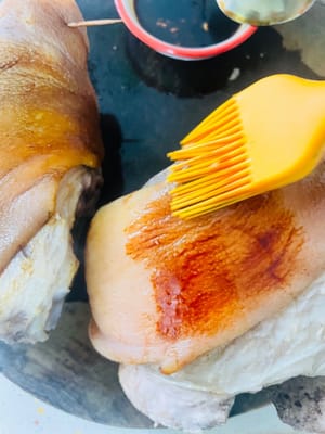 Die Schwarte einstechen und die Sauce auftragen. Die Feuchtigkeit vom Schweinshaxen mit Küchenpapier aufsaugen. Die Schwarte mit einer Gabel fest einstechen (damit sie die Aromen besser aufnimmt) und braten, bis sie ein tigerfellartiges Muster entwickelt. Anschließend die Farbsauce mehrmals mit einem Pinsel auftragen, um eine gleichmäßige Farbe zu erzielen.