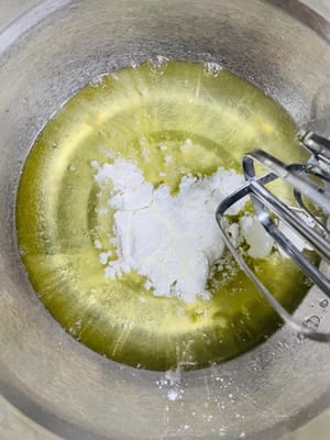 Batir claras de huevo: Añadir el zumo de limón y la maicena al bol con las claras. Añadir el azúcar a las claras en 3 tandas y batir con una batidora eléctrica hasta que se formen picos firmes (los picos deben mantenerse erguidos al levantar las varillas).