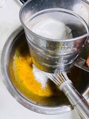 Agregar la harina y mezclar la masa: Tamizar la harina para pasteles, agregar las nueces picadas, el polvo para hornear y el bicarbonato de sodio, y mezclar hasta que no queden partículas de harina seca (puede omitir el polvo para hornear y el bicarbonato de sodio si no le gustan los agentes leudantes).